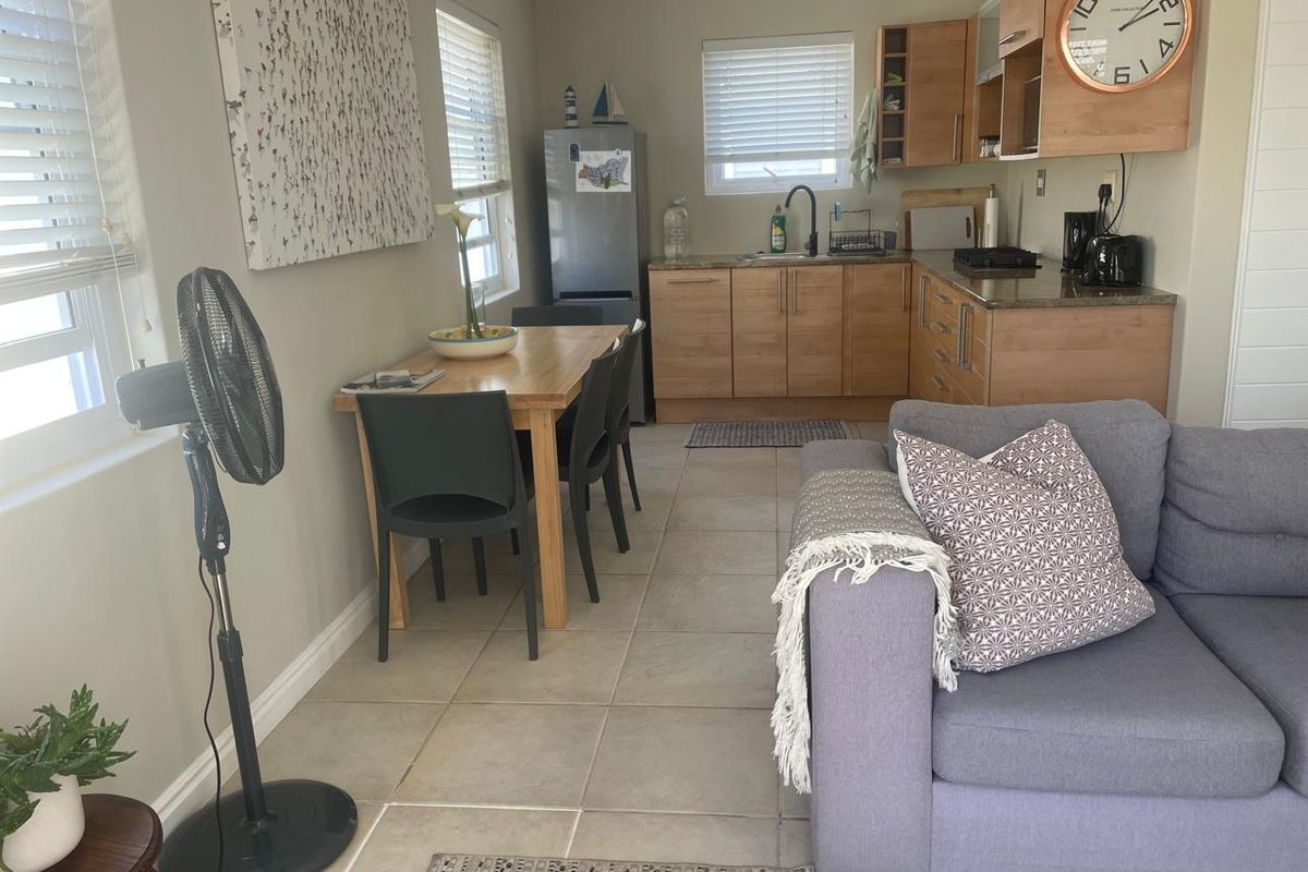 Open-plan living and kitchen area featuring tiled flooring, light wood cabinetry, granite countertops, and integrated cooking facilities.