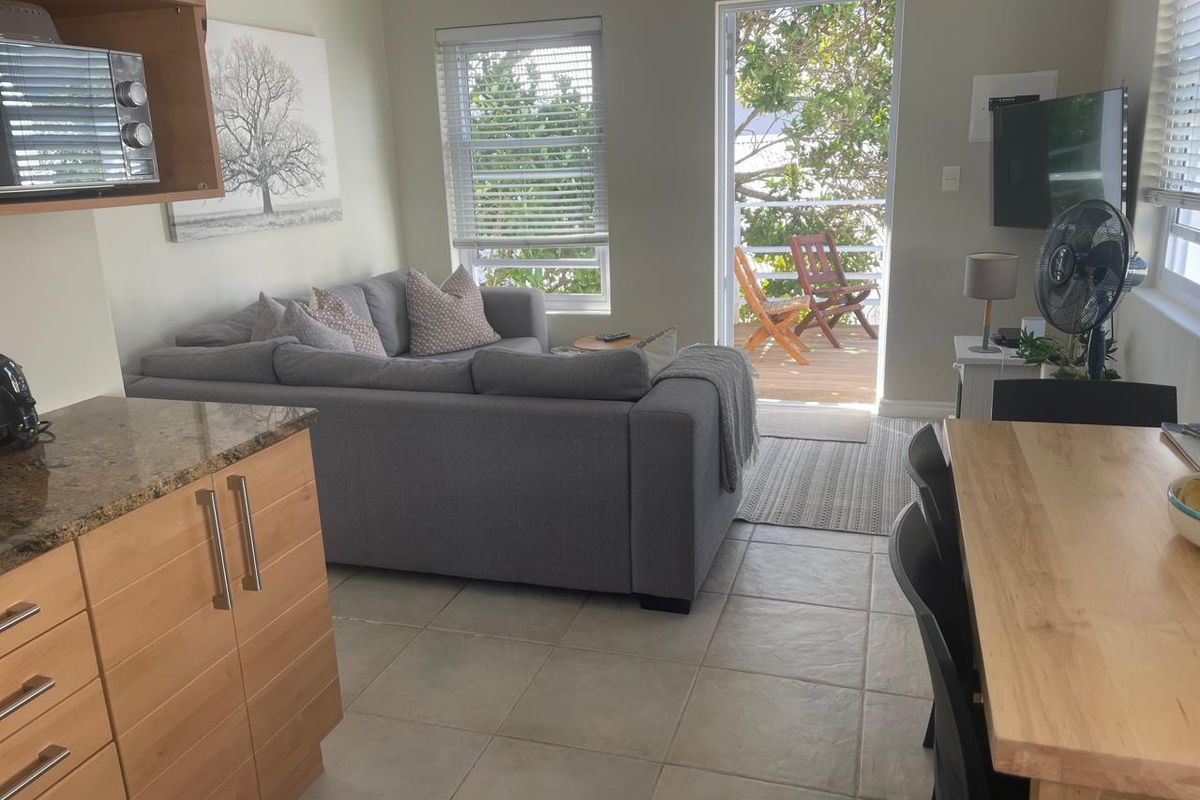 Open-plan living and kitchen area featuring tiled floors, granite countertops, and direct access to a private balcony through a sliding door.