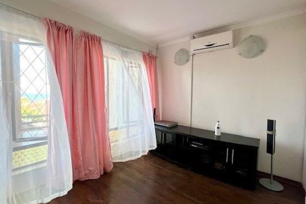 A bedroom featuring laminate flooring, built-in cupboards, and a wall-mounted air conditioning unit, with large windows providing natural light.