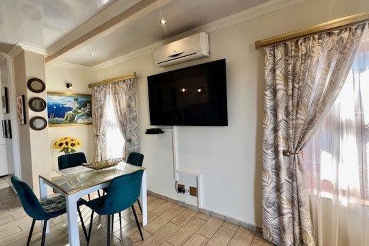 A well-maintained living area featuring tiled flooring, recessed downlighting, and a wall-mounted air conditioning unit.