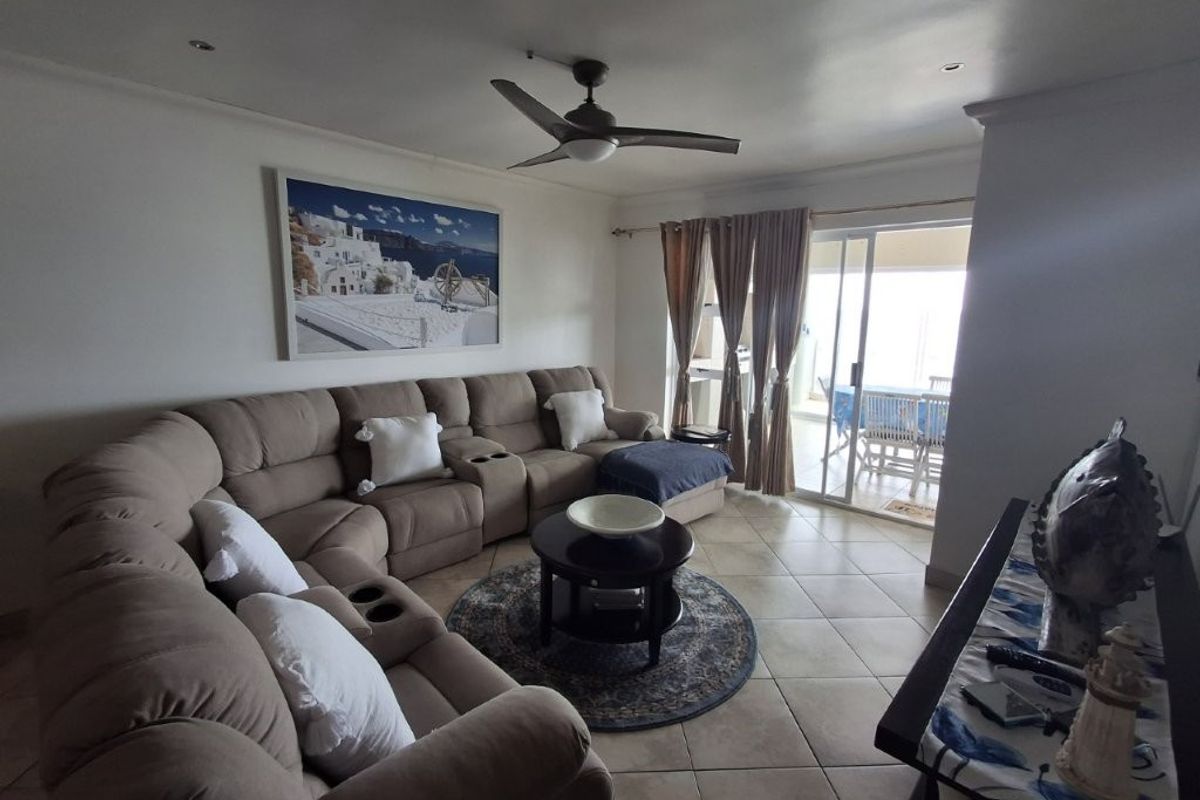 A comfortable living room featuring tiled flooring, a ceiling fan, and large sliding glass doors that provide access to an outdoor patio area.