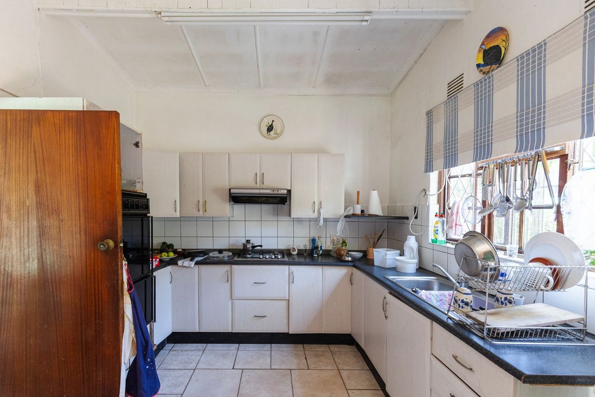 A functional kitchen featuring built-in cabinetry, a gas hob, extractor fan, and tiled finishes, offering potential for modernization and cosmetic updates.