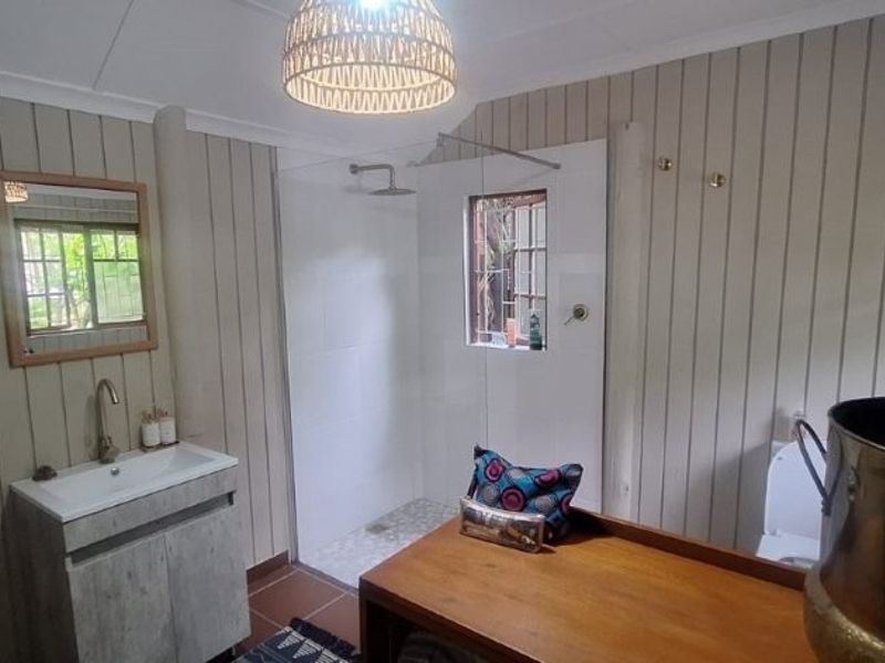 A bathroom featuring timber wall paneling, a modern vanity with basin, a walk-in shower enclosure, and a toilet.