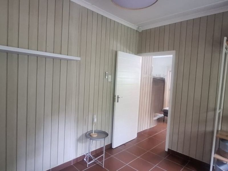 A bedroom featuring vertical timber wall paneling and tiled flooring, providing a neutral base for interior design updates.