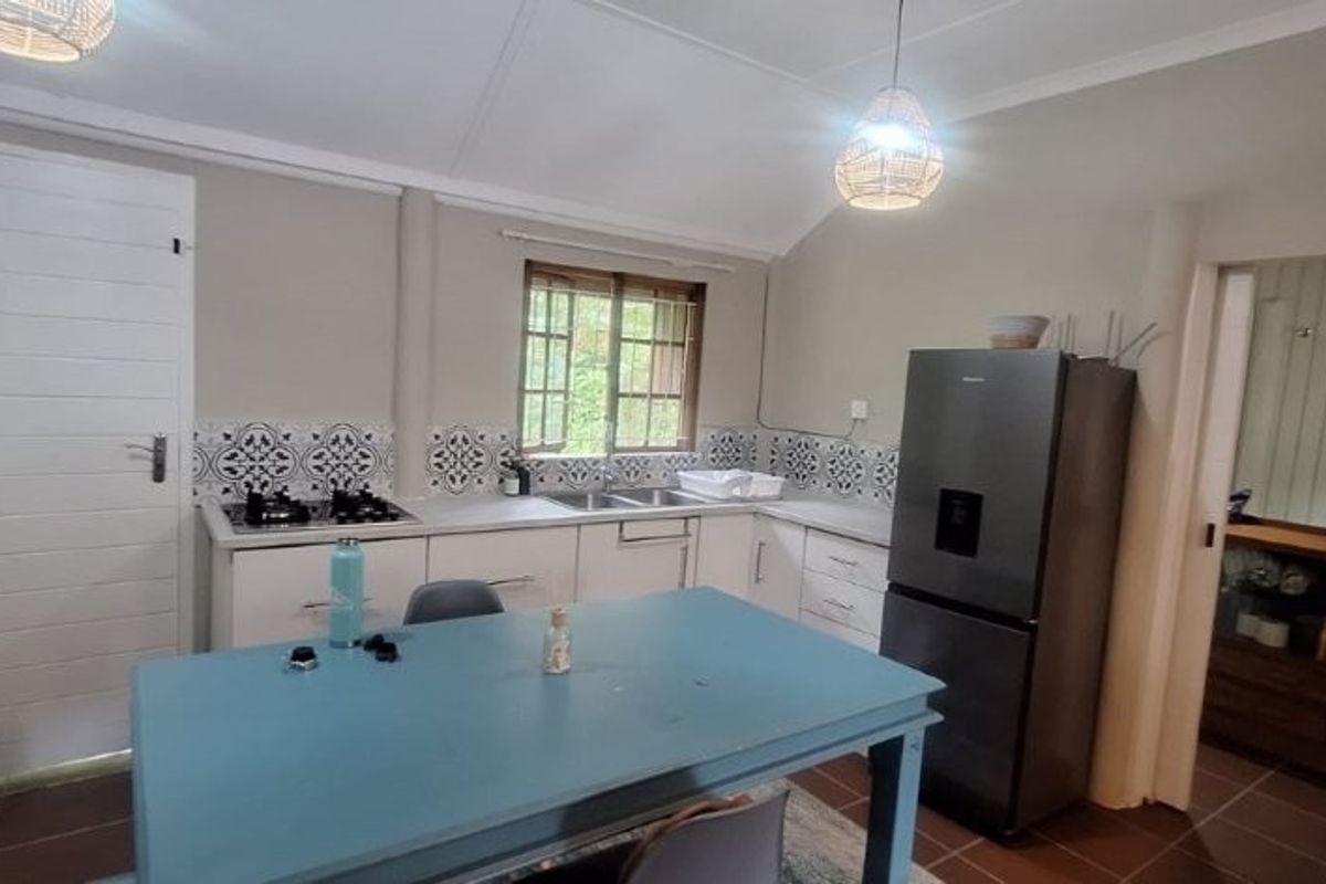 A functional kitchen featuring built-in cabinetry, a gas hob, tiled backsplash, and tiled flooring, with an adjacent doorway leading to a secondary space.