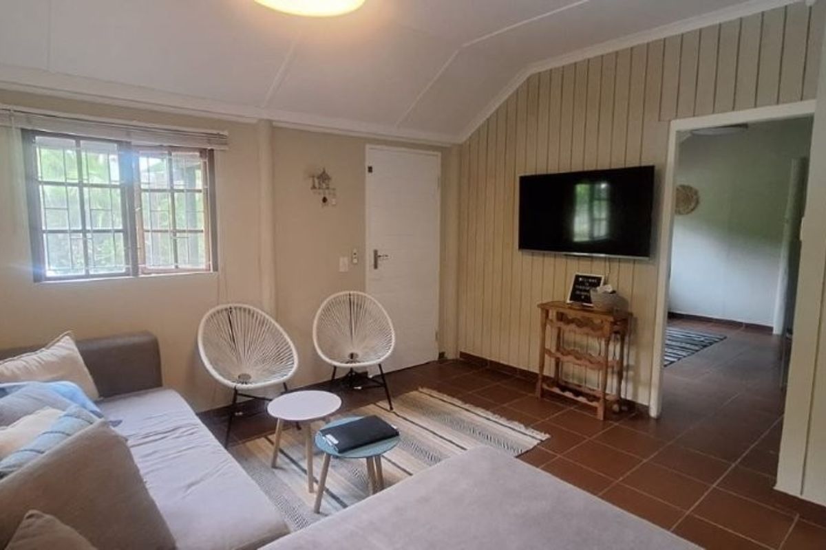 A living room featuring tiled flooring, a vaulted ceiling, and security bars on the windows, providing a functional and well-lit living space.