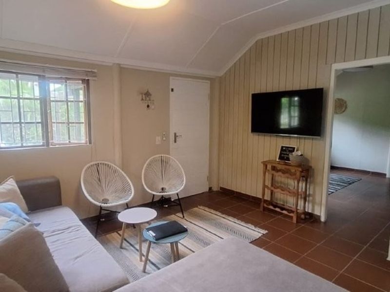 A living room featuring tiled flooring, a vaulted ceiling, and security bars on the windows, providing a functional and well-lit living space.
