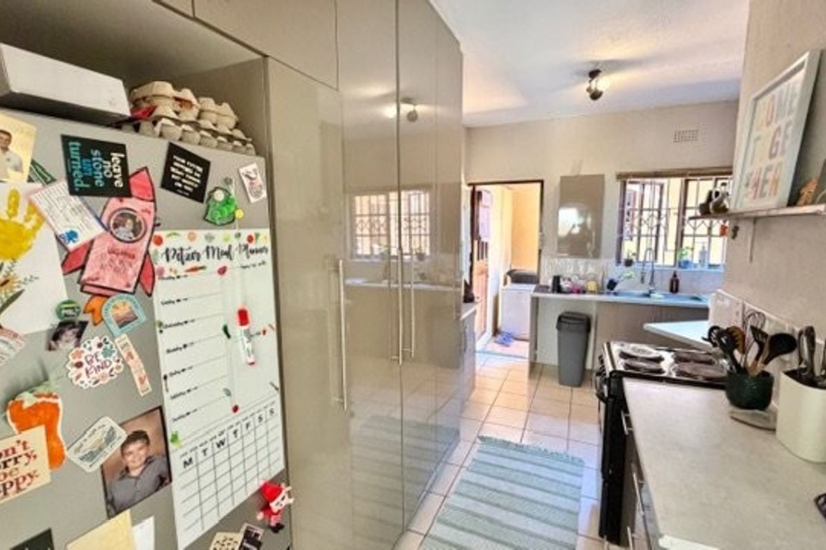 Functional kitchen featuring high-gloss cabinetry, electric stove, and tiled flooring, with a direct view through to the laundry area.