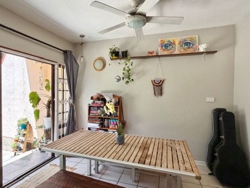 Dining area featuring tiled flooring, a ceiling fan, and large sliding glass doors providing direct access to the outdoor patio space.