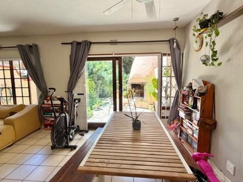 Open plan living and dining area featuring tiled flooring, a ceiling fan, and sliding glass doors providing access to the outdoor patio.