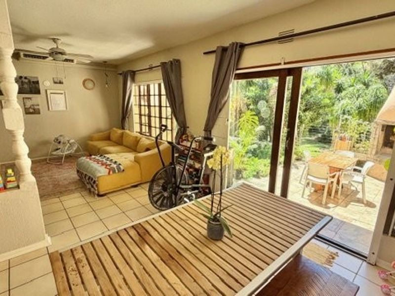 Open-plan living area featuring tiled flooring and large sliding glass doors that provide seamless access to the outdoor patio and garden.