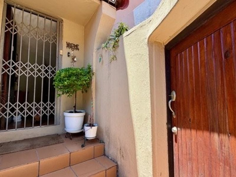 Entrance area featuring a security gate, tiled steps, and a wooden door.