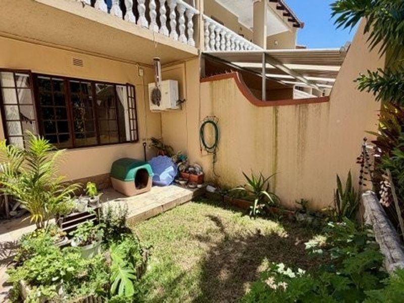 A private rear courtyard featuring a small lawn, tiled patio area, and boundary wall, providing a functional outdoor space for the townhouse.