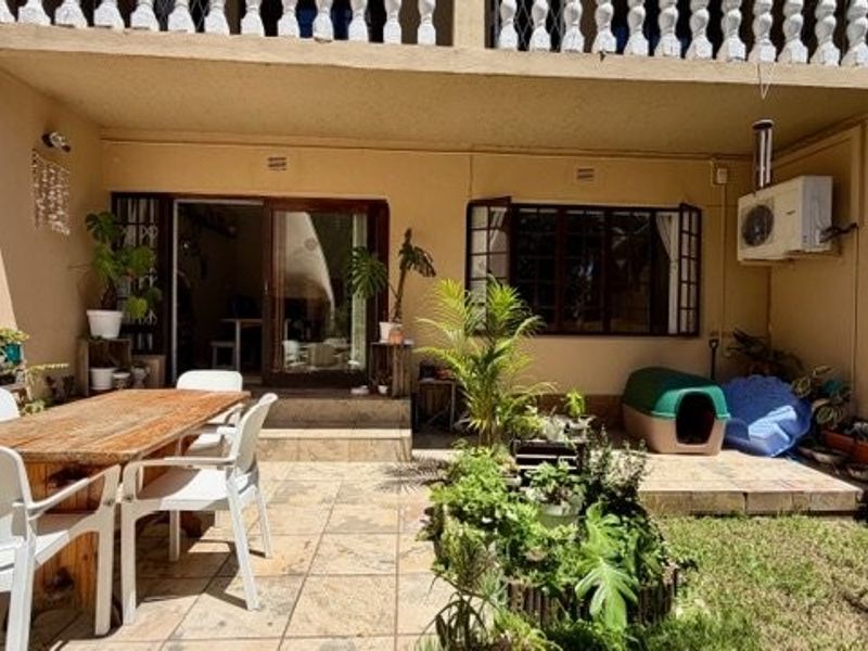 A covered patio area featuring tiled flooring, direct access to the interior via sliding doors, and an external air conditioning unit.