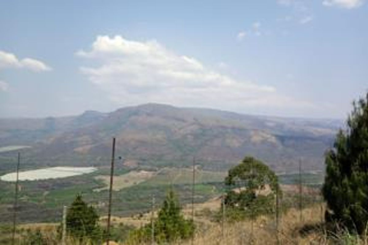 A scenic landscape view overlooking the farm property, featuring rolling hills and distant mountains.