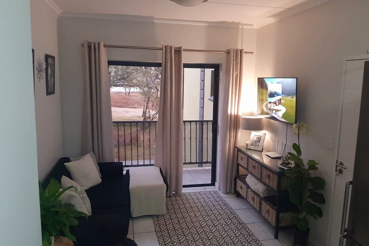A compact living room featuring tiled flooring and a sliding glass door that opens onto a balcony.