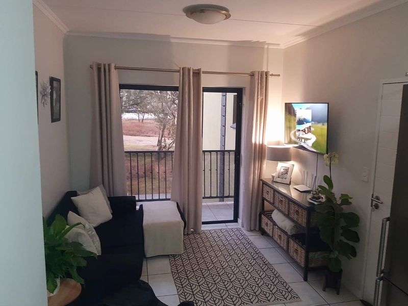 A compact living room featuring tiled flooring and a sliding glass door that opens onto a balcony.