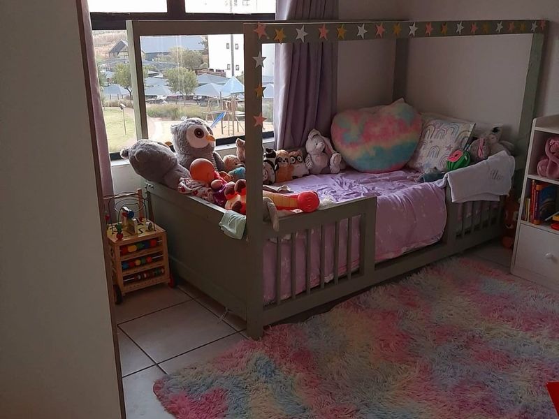 A bright bedroom featuring tiled flooring and a large window that provides natural light and views of the surrounding area.