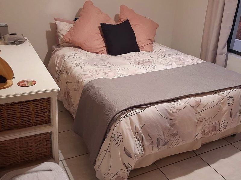 A cozy bedroom featuring tiled flooring and neutral wall finishes, providing a functional and comfortable sleeping space.