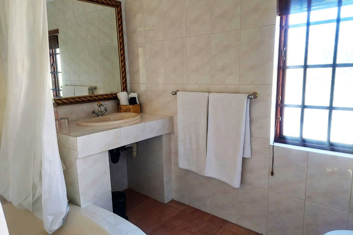 A functional bathroom featuring a tiled vanity with a drop-in basin, wall-mounted mirror, and ceramic wall and floor tiling.