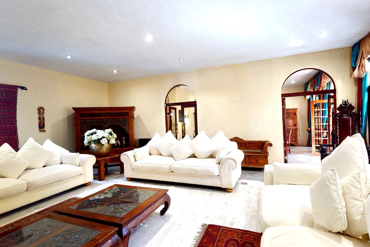 Spacious living room featuring textured walls, recessed lighting, and arched architectural openings leading to adjacent areas.