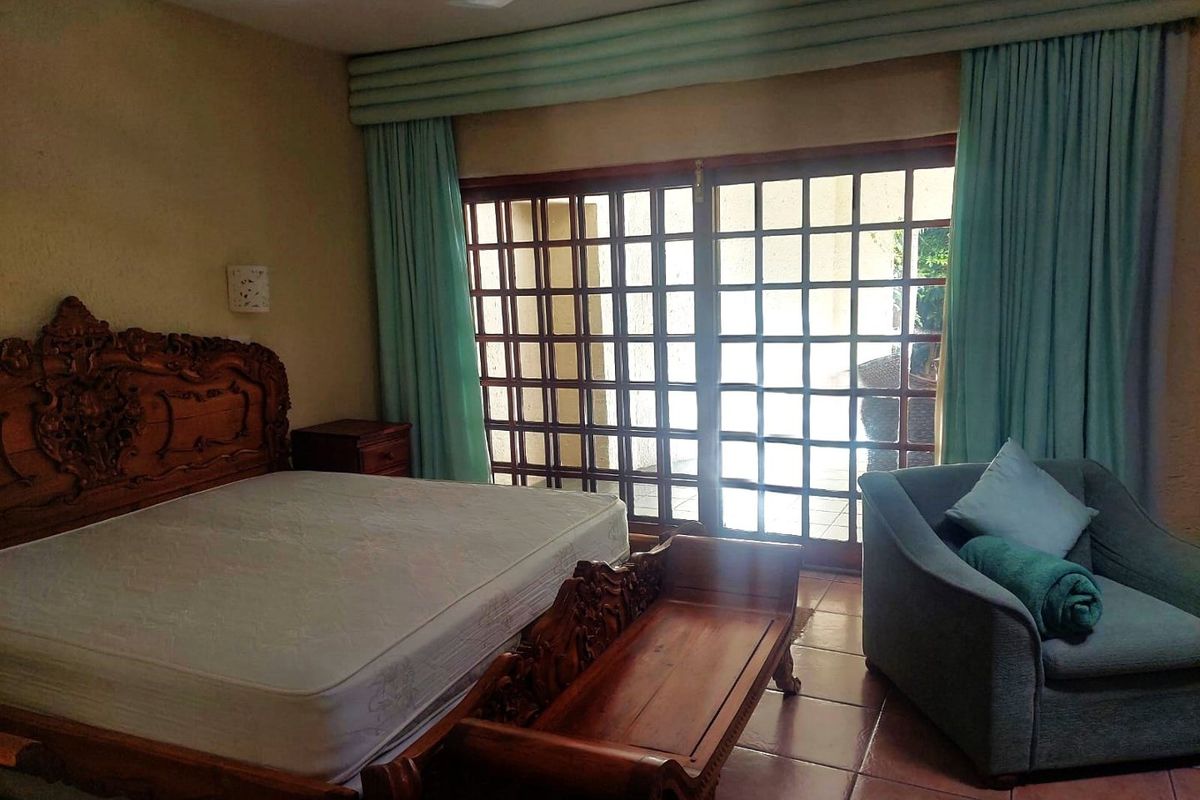 Spacious bedroom featuring tiled flooring, a ceiling fan, and large wooden grid sliding doors providing access to the exterior.