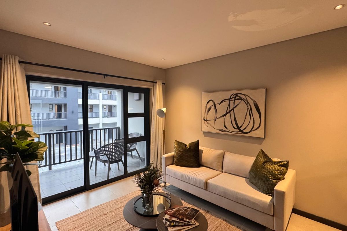 A well-lit living room featuring tiled floors, recessed lighting, and large sliding glass doors that provide direct access to a private balcony.