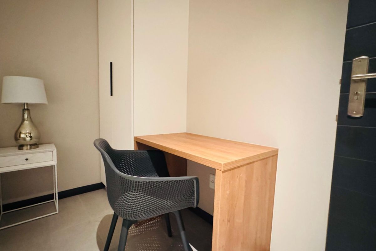 A bedroom corner featuring a built-in wardrobe and a compact wooden desk, providing functional storage and workspace.