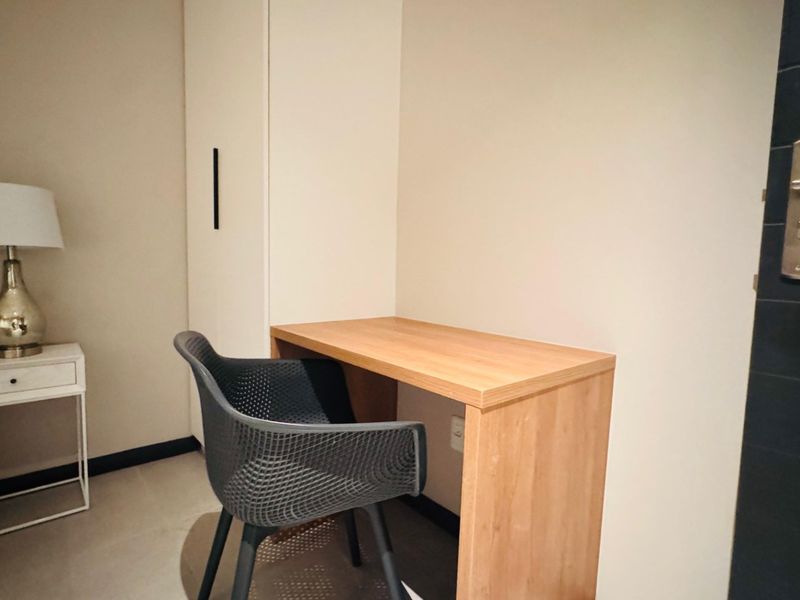 A bedroom corner featuring a built-in wardrobe and a compact wooden desk, providing functional storage and workspace.