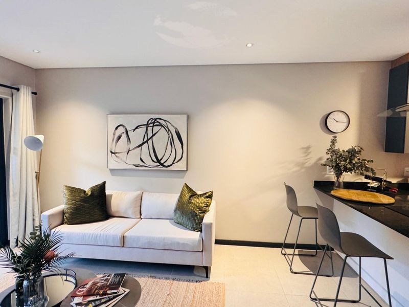Modern open-plan living area featuring a sleek kitchen with granite countertops, integrated extractor fan, and seamless flow to a private balcony.