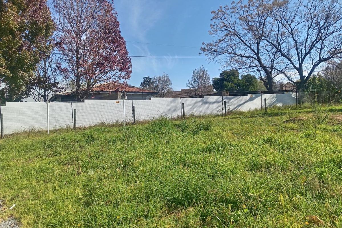 A view of an undeveloped rear yard area featuring perimeter fencing with integrated electric security wires.