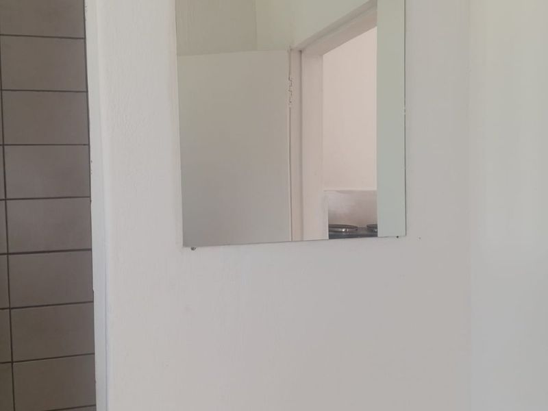 A simple bathroom interior featuring a wall-mounted mirror and tiled wall finishes.