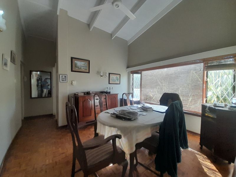 Dining room featuring parquet flooring, a vaulted ceiling with a fan, and large windows with security bars.