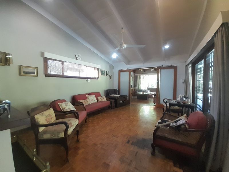 Spacious living room featuring vaulted ceilings, parquet flooring, and sliding glass doors that provide access to the outdoor area.