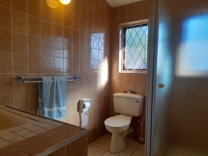 A dated bathroom featuring ceramic wall and floor tiles, a built-in bathtub, a separate shower enclosure, and a standard toilet.