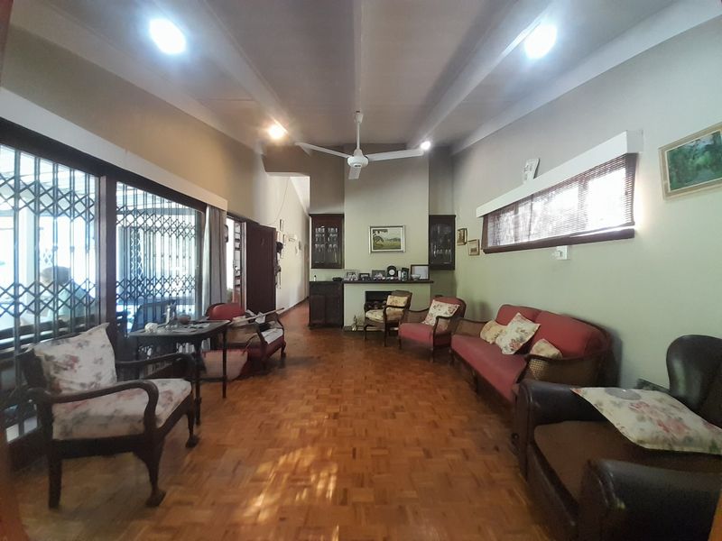 Spacious living room featuring classic parquet flooring, a built-in fireplace, and integrated cabinetry, offering a warm and traditional atmosphere.