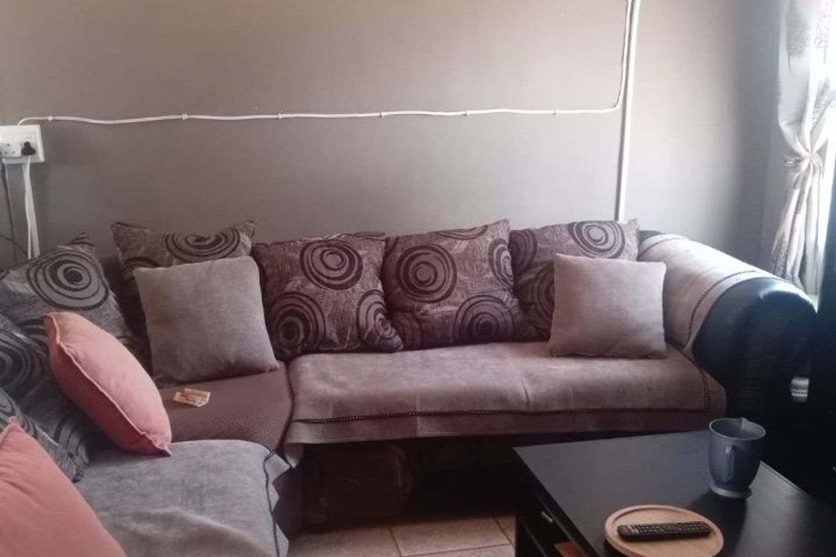 A living room area featuring tiled flooring and visible surface-mounted electrical wiring and distribution board.