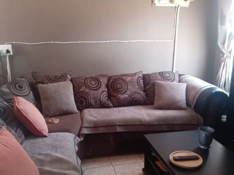A living room area featuring tiled flooring and visible surface-mounted electrical wiring and distribution board.