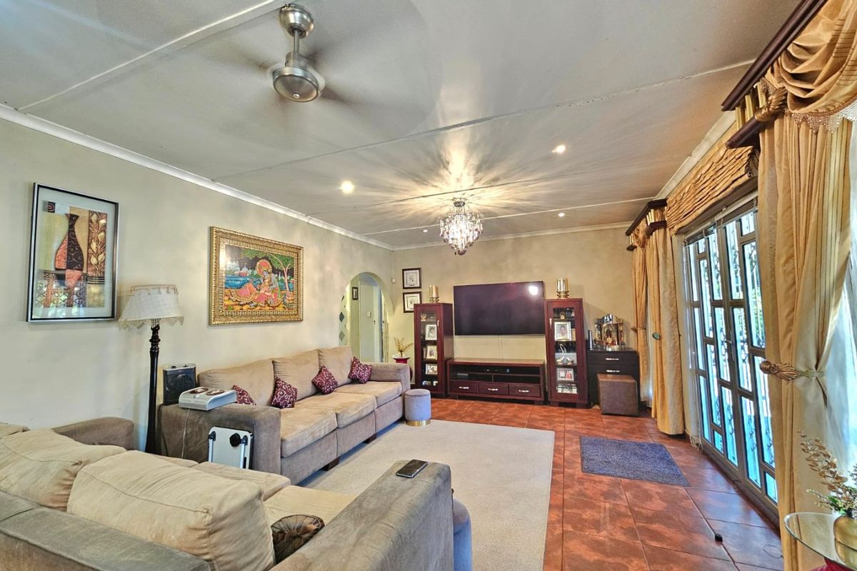 Spacious living room featuring tiled flooring, a ceiling fan, decorative chandelier, and sliding glass doors providing access to the exterior.