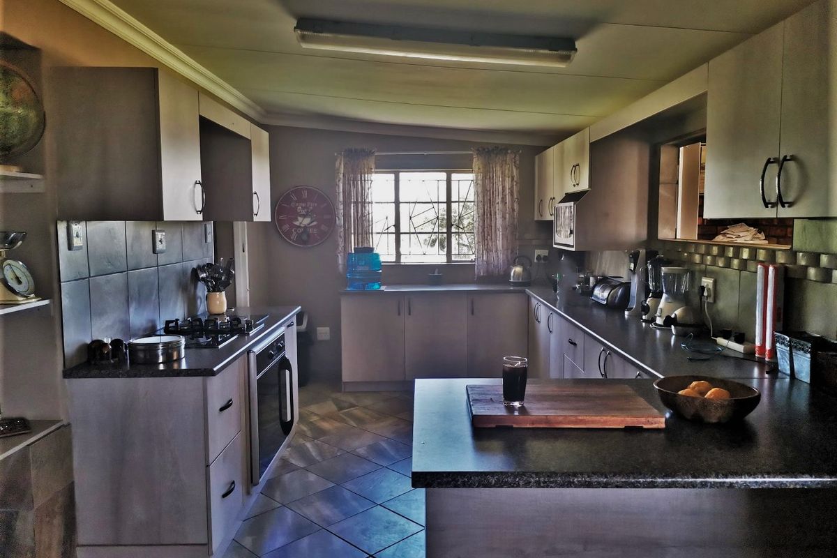A functional kitchen featuring built-in cabinetry, a gas hob, an integrated oven, and tiled flooring with a central island workspace.