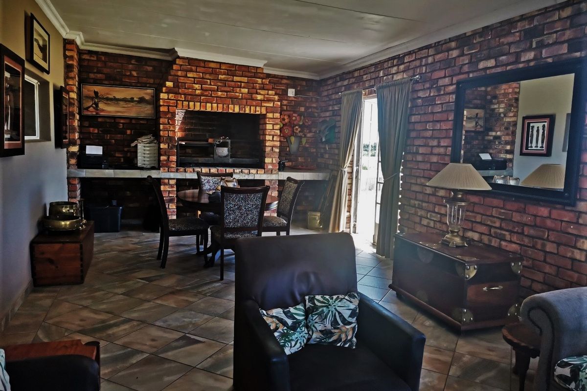 Spacious living area featuring exposed brick walls, tiled flooring, and a large built-in brick fireplace, providing a rustic and cozy atmosphere.