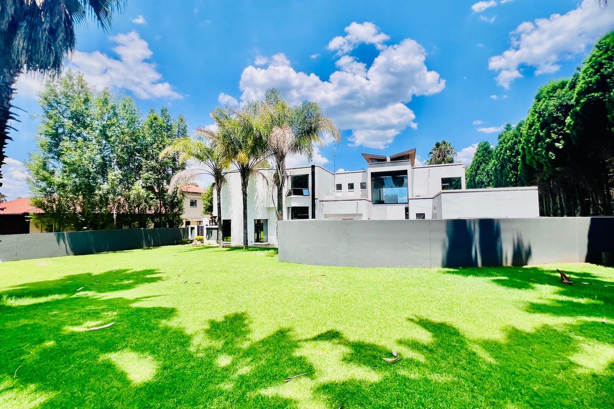 A spacious rear garden featuring a well-maintained lawn and a modern architectural building facade with clean lines.