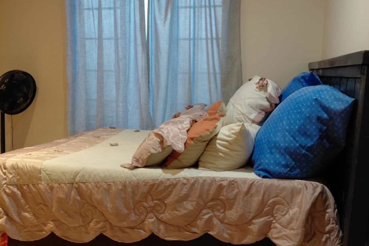 A bedroom featuring tiled flooring and a window with curtain tracks, providing a functional and neutral living space.