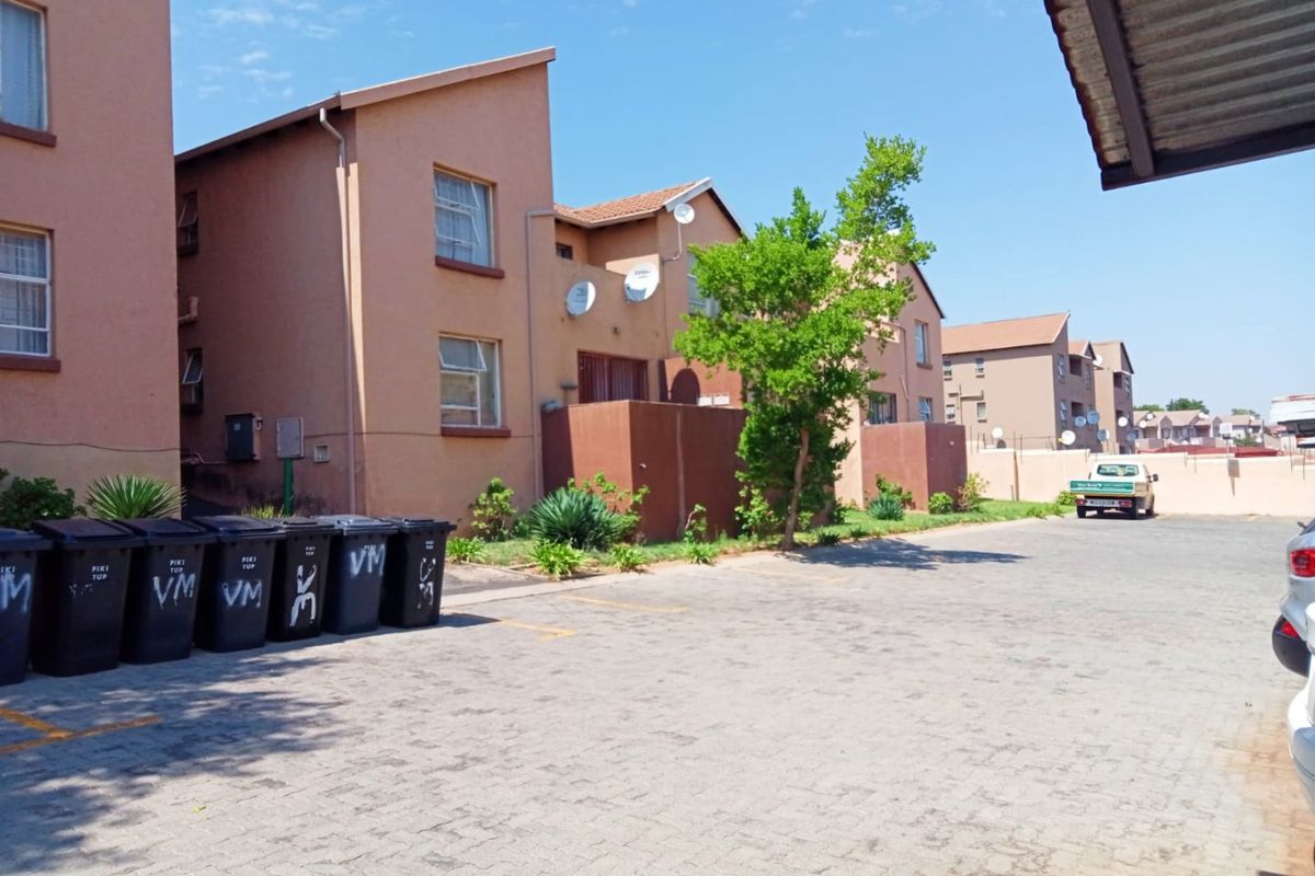 Exterior view of a multi-story apartment complex featuring paved parking areas and residential building facades.