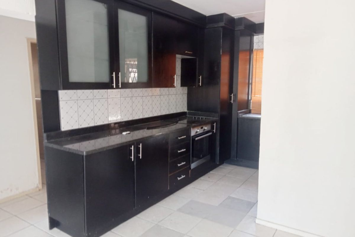 A functional kitchen featuring dark cabinetry, granite-style countertops, a built-in oven, and tiled backsplash, offering a clean and practical workspace.
