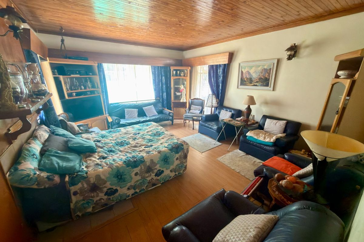 Spacious living room featuring a distinctive timber-clad ceiling, laminate flooring, and integrated built-in cabinetry, offering a traditional aesthetic with potential for modernization.