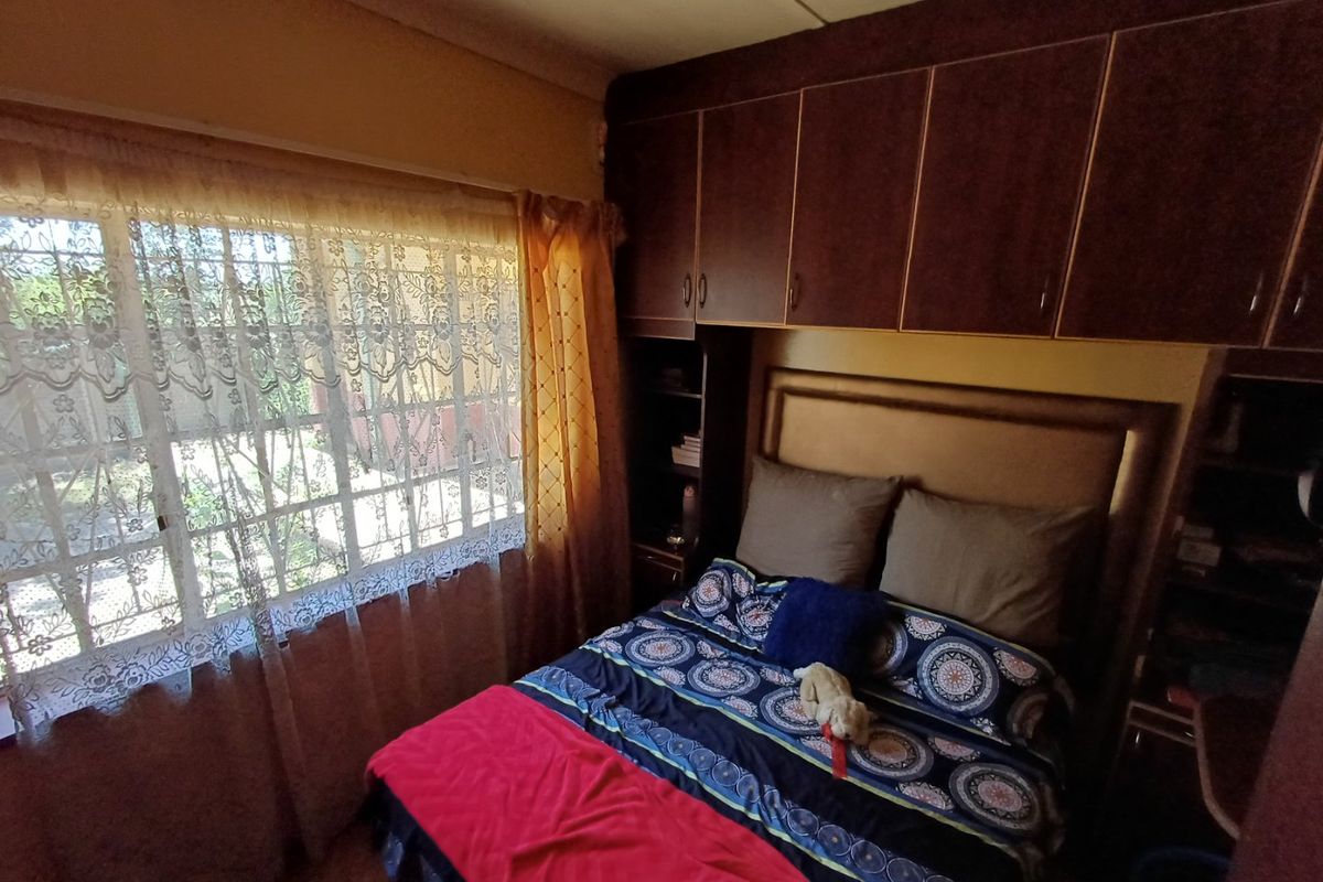 A bedroom featuring built-in cabinetry and security bars on the window, offering a functional space with potential for cosmetic updates.