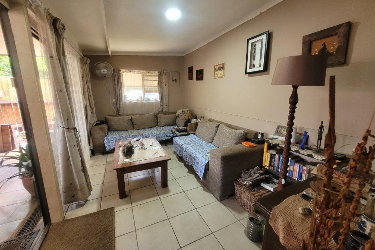 A living room featuring tiled flooring, recessed lighting, and a sliding glass door providing access to the outdoor area.