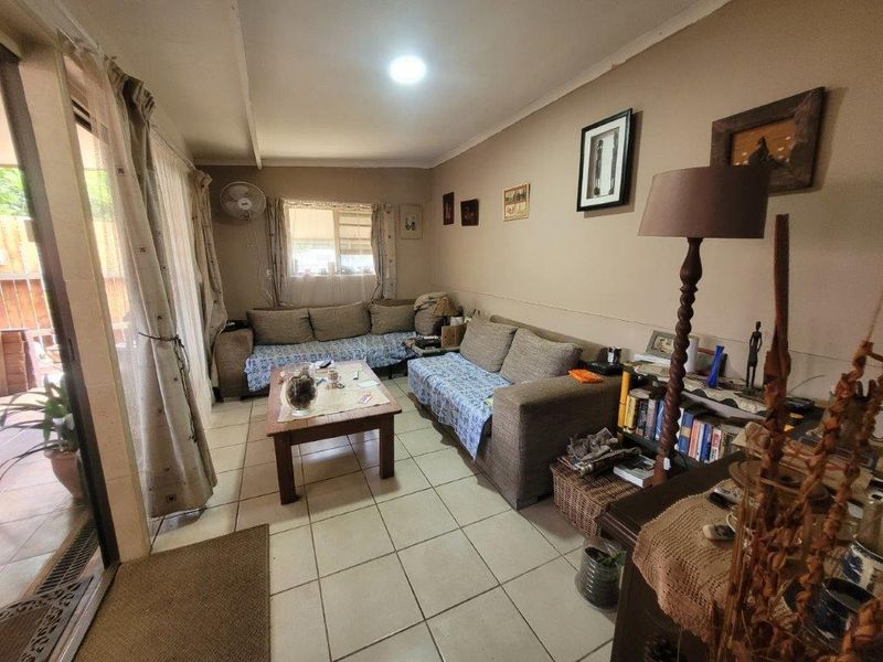 A living room featuring tiled flooring, recessed lighting, and a sliding glass door providing access to the outdoor area.