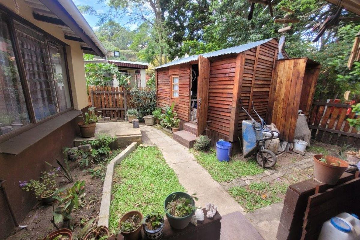 Rear garden area featuring a timber storage shed, paved pathways, and established boundary fencing, offering potential for landscaping and outdoor utility space.
